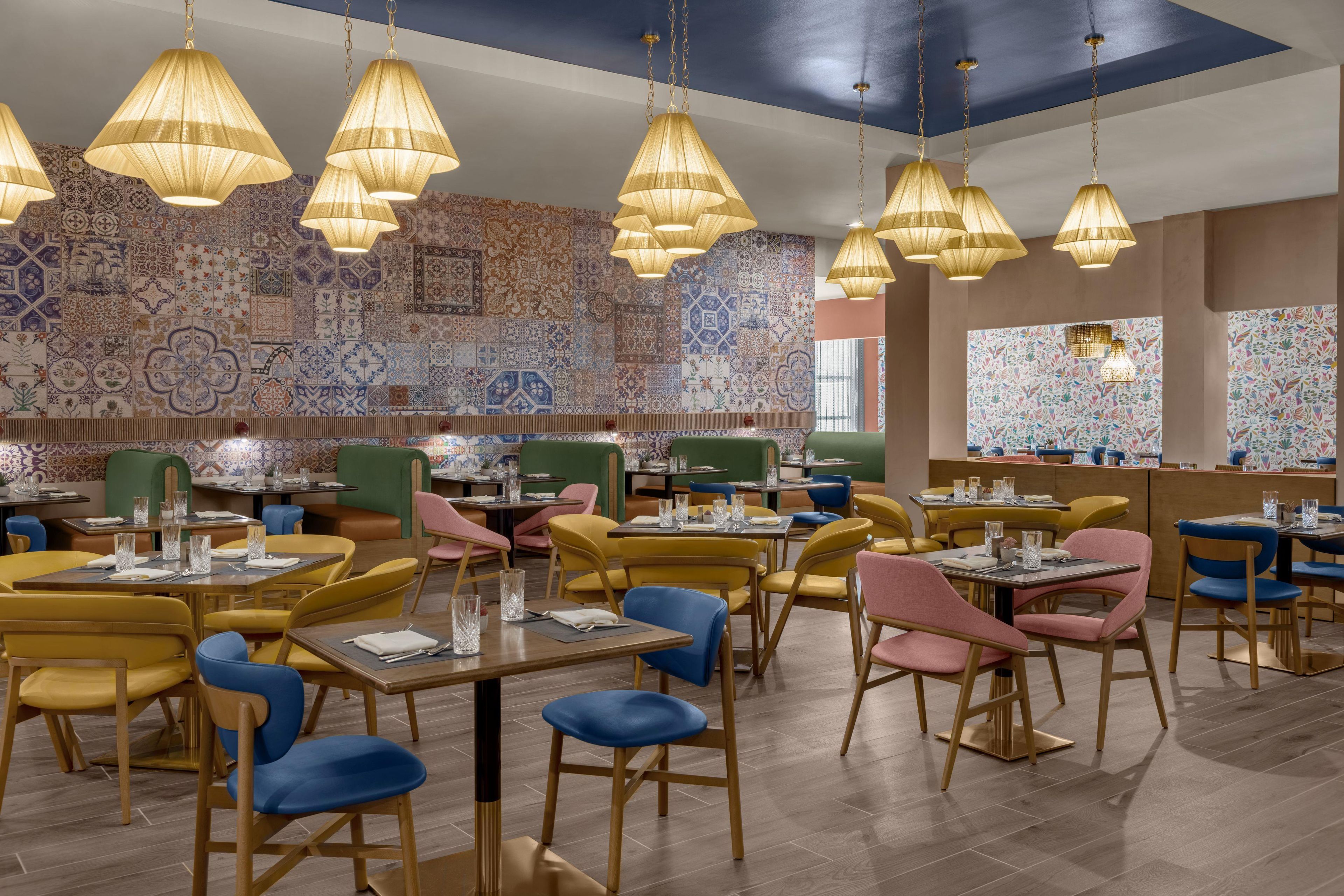 A restaurant interior with multiple dining tables, chairs, and hanging pendant lights.