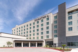 Um edifício moderno de hotel com fachada plana, várias janelas e uma placa indicando ser um empreendimento Hilton.