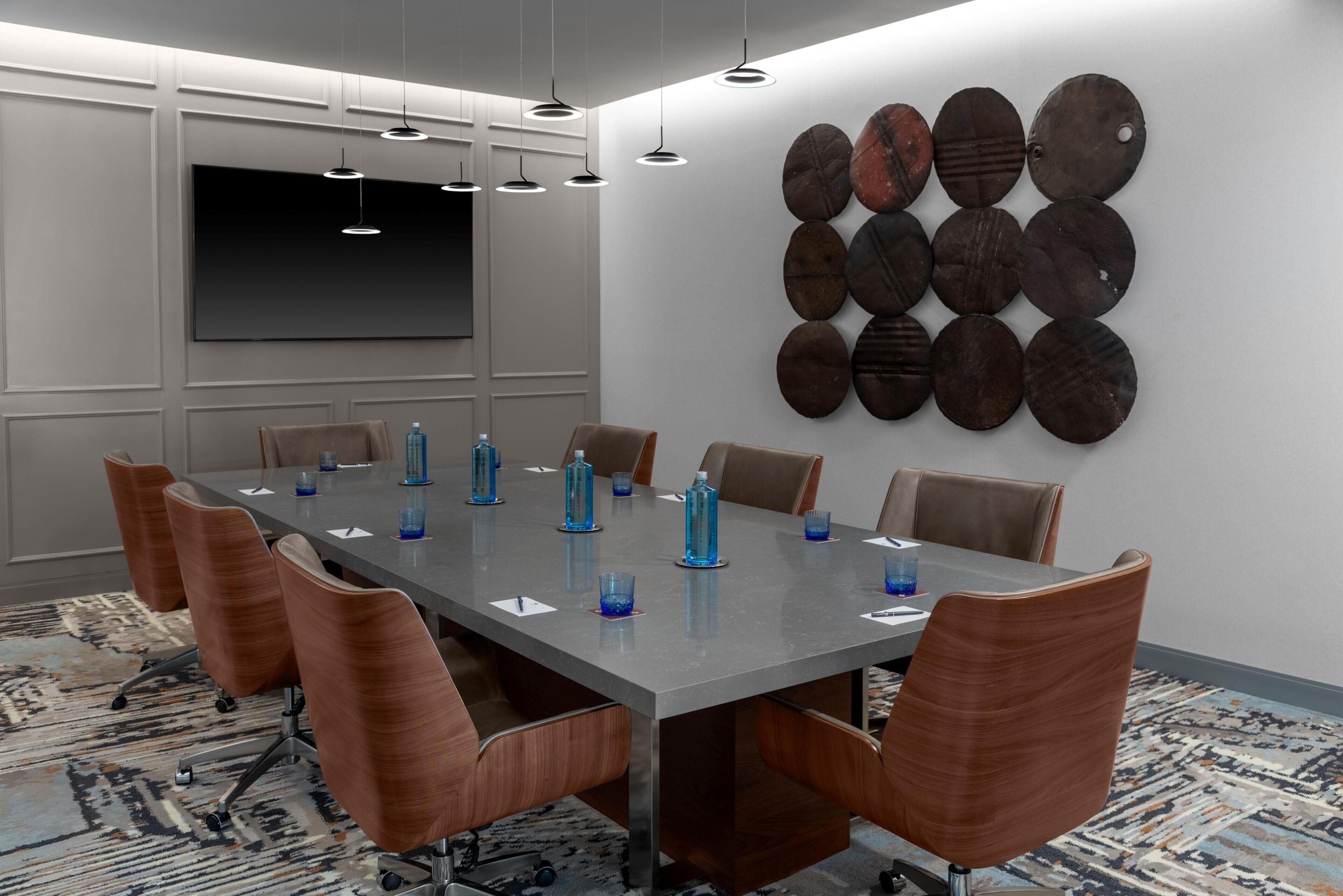 A conference room with a long table, chairs, and a wall-mounted art piece.