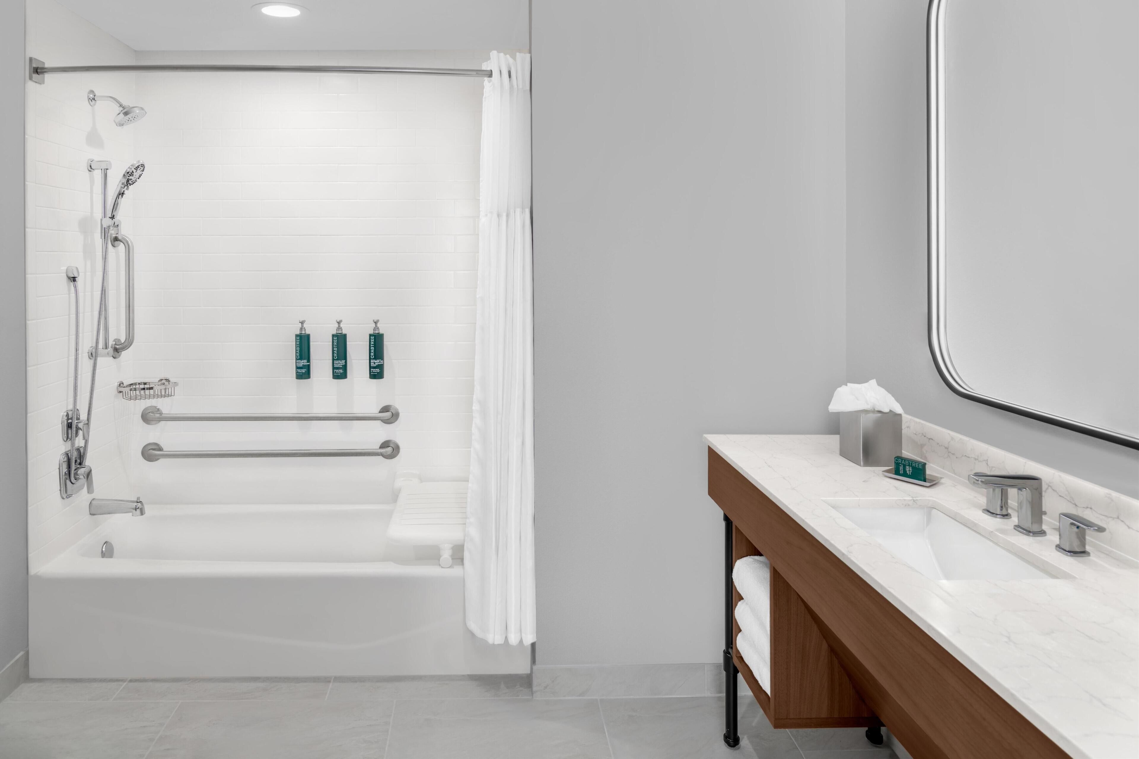 Un baño moderno con bañera, ducha y tocador con espejo.