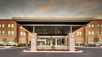 A hotel entrance with a covered waiting area, multiple windows, and a brick facade.