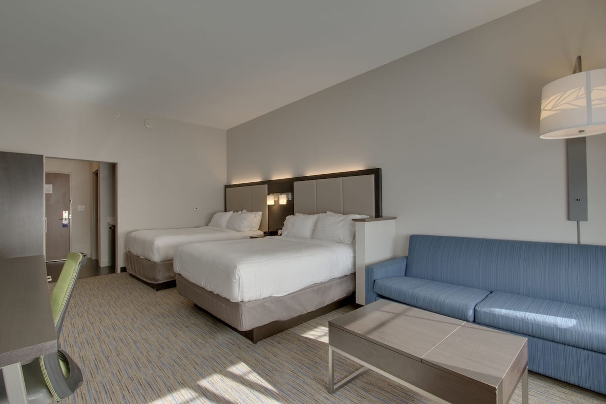 Een hotelkamer met twee bedden, een bank, een bureau en een lamp.