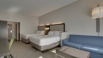 A hotel room with two beds, a sofa, a desk, and a lamp.