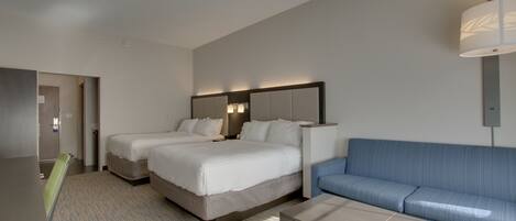 Habitación de hotel con dos camas, un sofá, un escritorio y una lámpara.