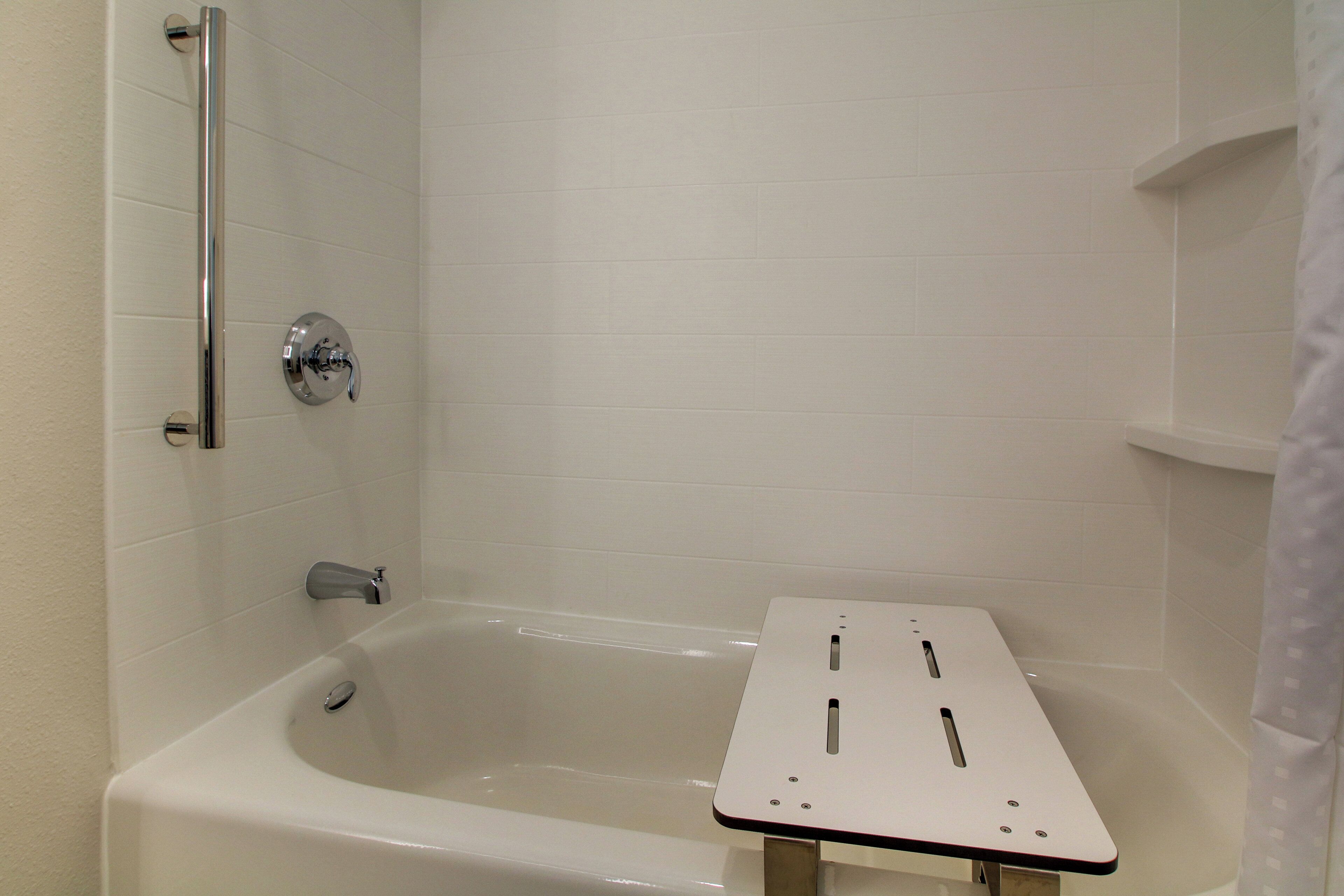 A bathroom with a bathtub, a shower area, and a small table.