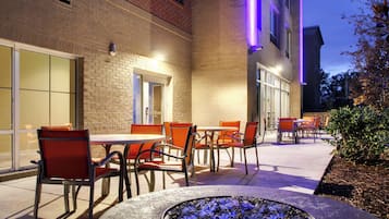 An outdoor patio area with brick walls, outdoor seating, and a fire feature.