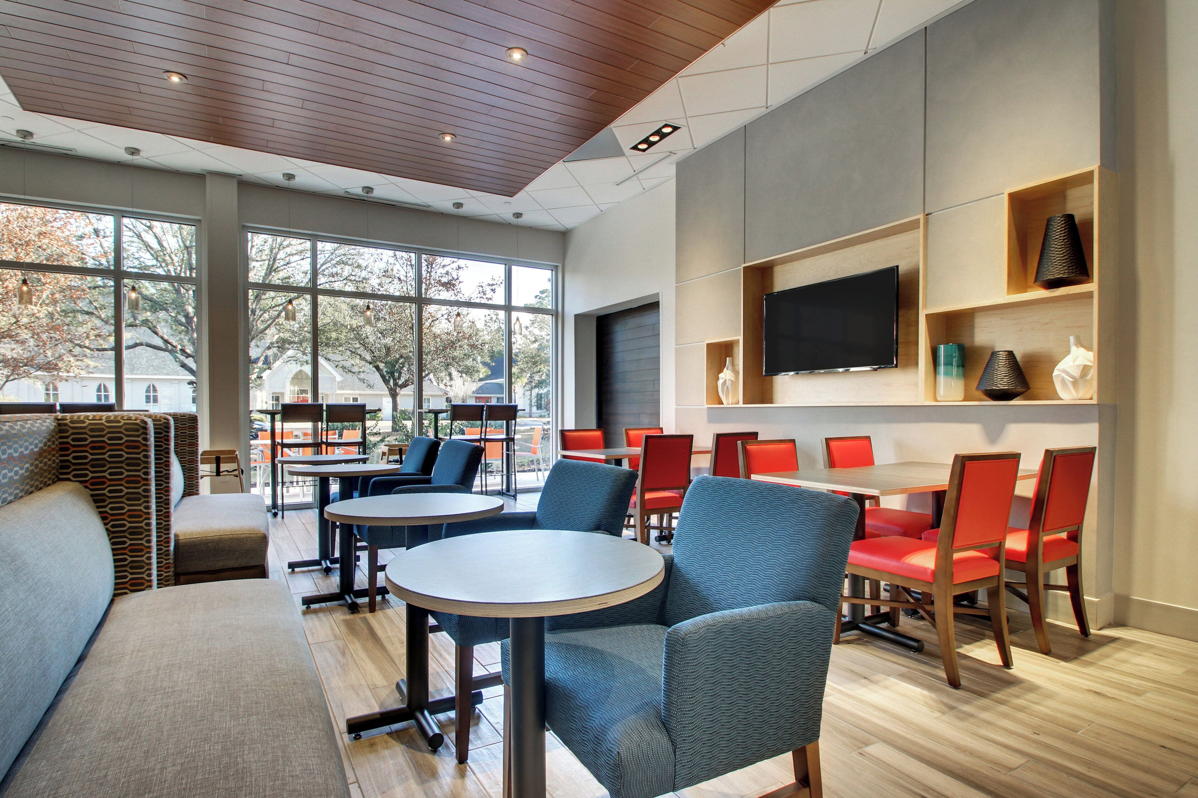 A modern interior with a seating area, tables, and a television on the wall.