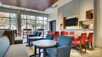 A modern interior with a seating area, tables, and a television on the wall.