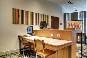 A modern office space with a long desk, two chairs, a computer, and a colorful abstract painting on the wall. - Holiday Inn Express & Suites Charleston NE Mt Pleasant US17 by IHG (Mount Pleasant)