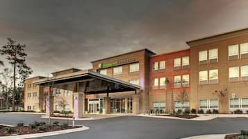 A Holiday Inn Express Suites hotel with a covered entrance, multiple windows, and a landscaped driveway.