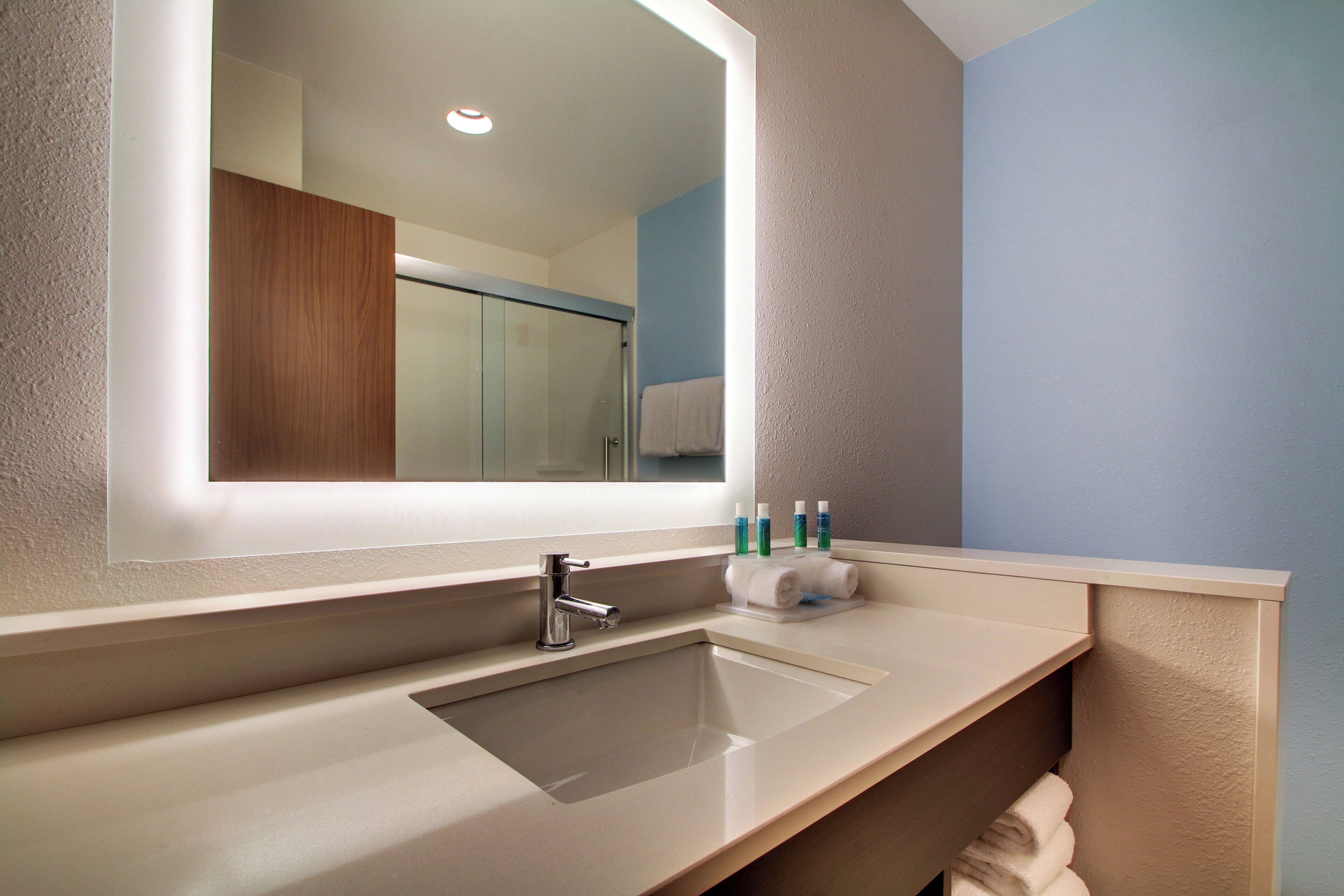 Un bagno moderno con uno specchio grande, un lavandino e un porta asciugamani.