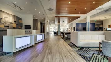 A hotel lobby with reception desks, seating areas, and a wooden ceiling.