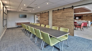 A conference room with a long table, yellow chairs, and a television on the wall.