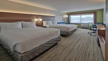 Habitación de hotel con dos camas, un escritorio, una silla y un ventanal grande.
