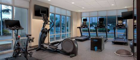 Ein modernes Fitnessstudio mit Ergometer, Laufbändern und einem Crosstrainer.