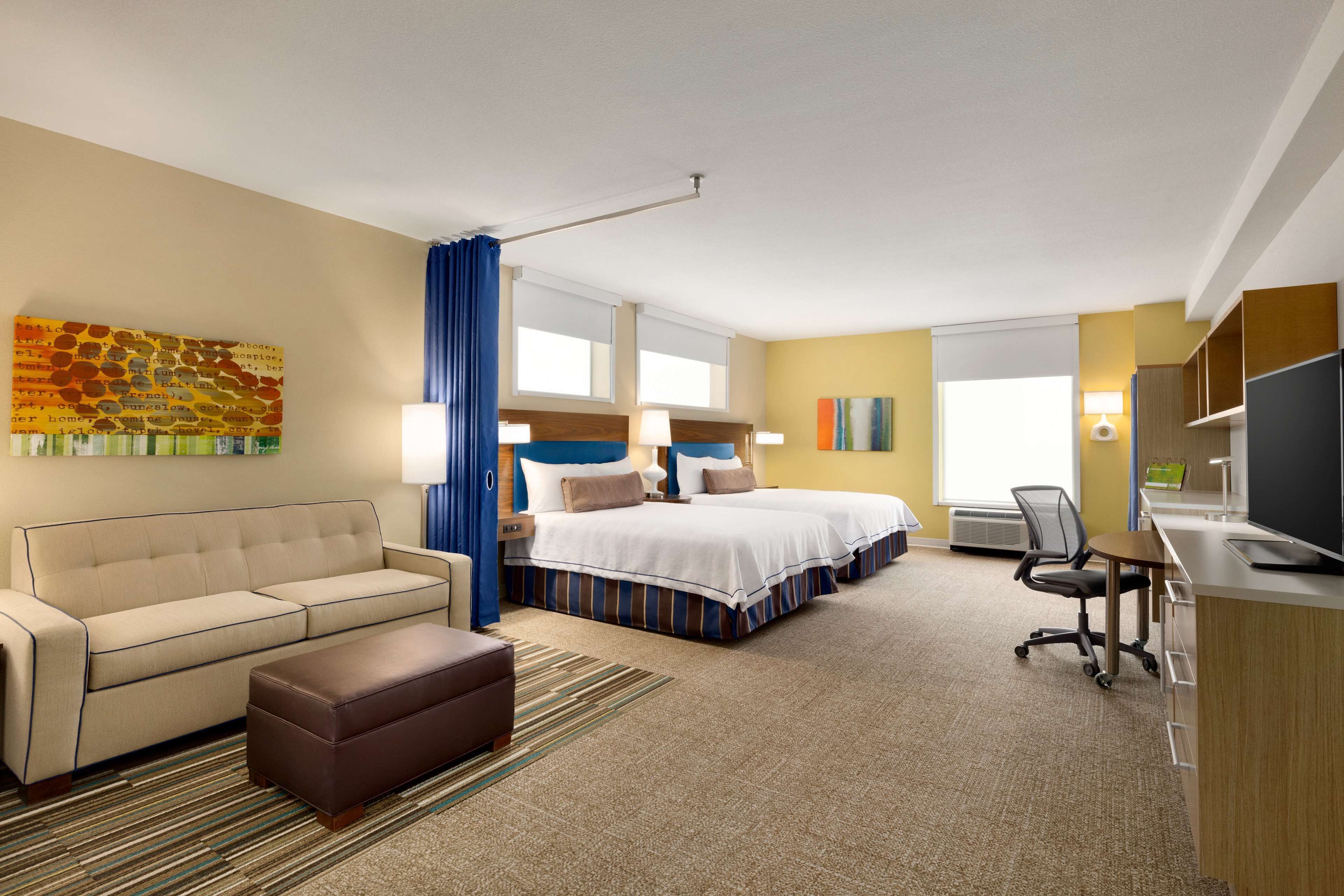A hotel room with a sofa, a bed, a desk, and a television.