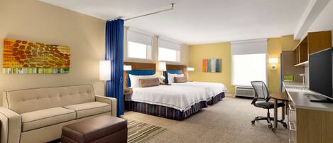 A hotel room with a sofa, a bed, a desk, and a television.