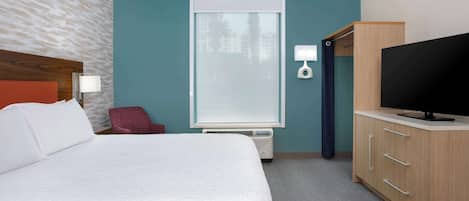 Una habitación de hotel con cama, televisión, escritorio y ventana con persianas.