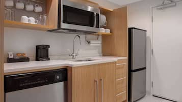 A modern kitchen with a stainless steel microwave, coffee maker, dishwasher, and a refrigerator.