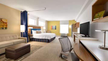 Una habitación de hotel con cama, escritorio, silla, sofá y televisión.