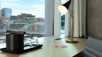 A modern desk with a tray holding glasses and a black container, a desk lamp, and a red card.