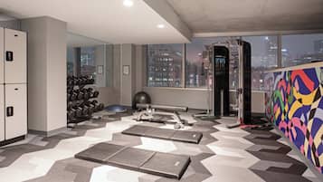 A gym with exercise equipment, a mirrored wall, and a city view.