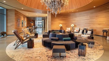 Un hall d’entrée spacieux avec un espace salon central, un lustre et un mur en bois.