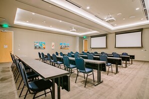 A conference room with multiple tables and chairs, a projector screen, and a ceiling-mounted projector. - Hotel Indigo Denver Downtown - Union Station by IHG (Denver)