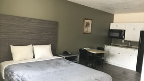 Ein Hotelzimmer mit Bett, Schreibtisch, Stuhl, Mikrowelle und Kühlschrank.