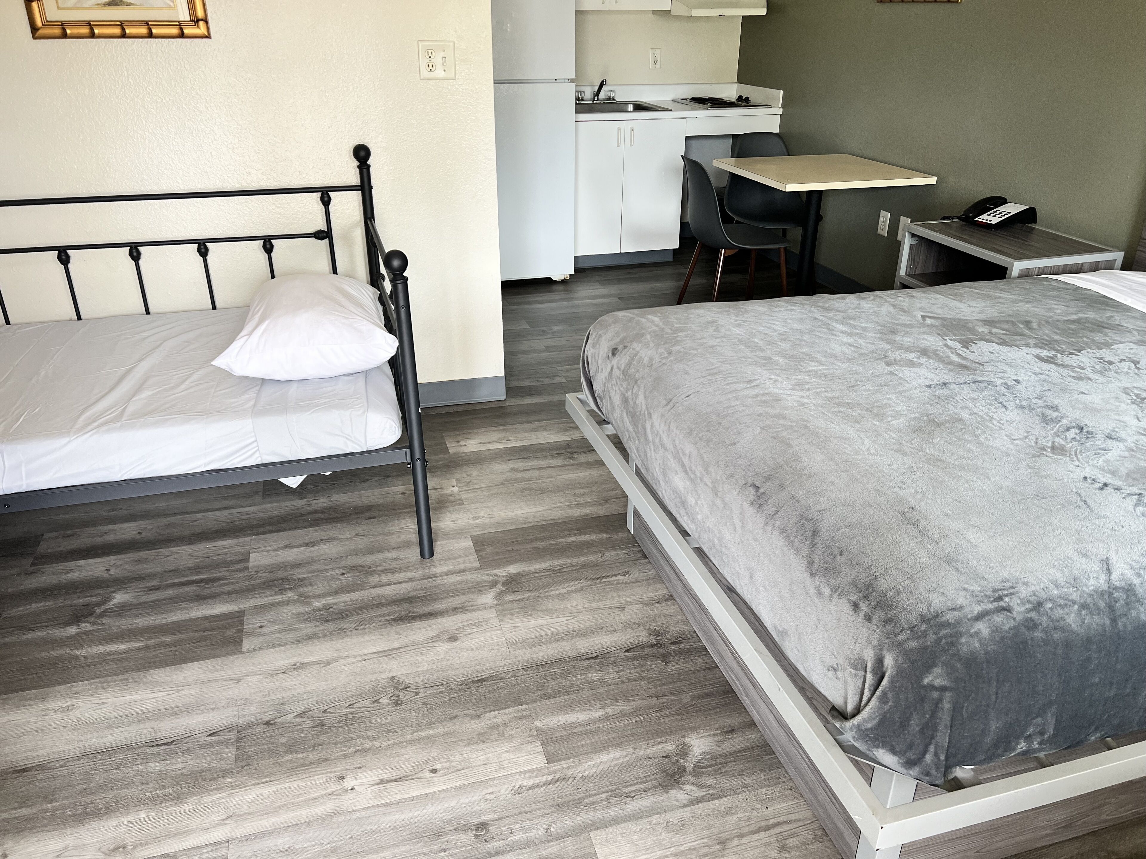 Una camera da letto con un letto, una scrivania e un angolo cottura.