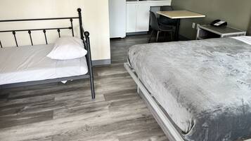 Una camera da letto con un letto, una scrivania e un angolo cottura.