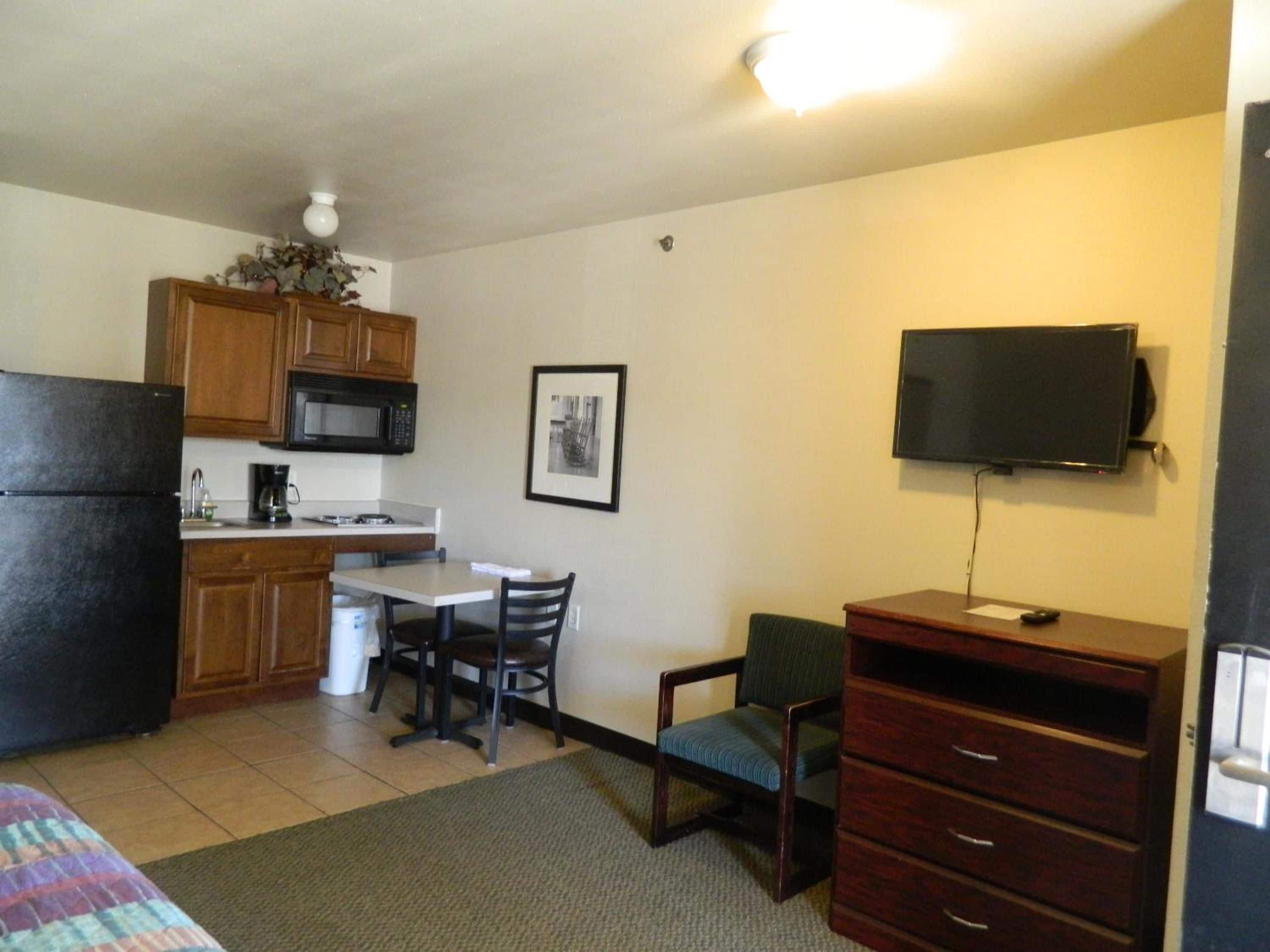 A compact living space with a kitchenette, a dining area, a television, and a bed.