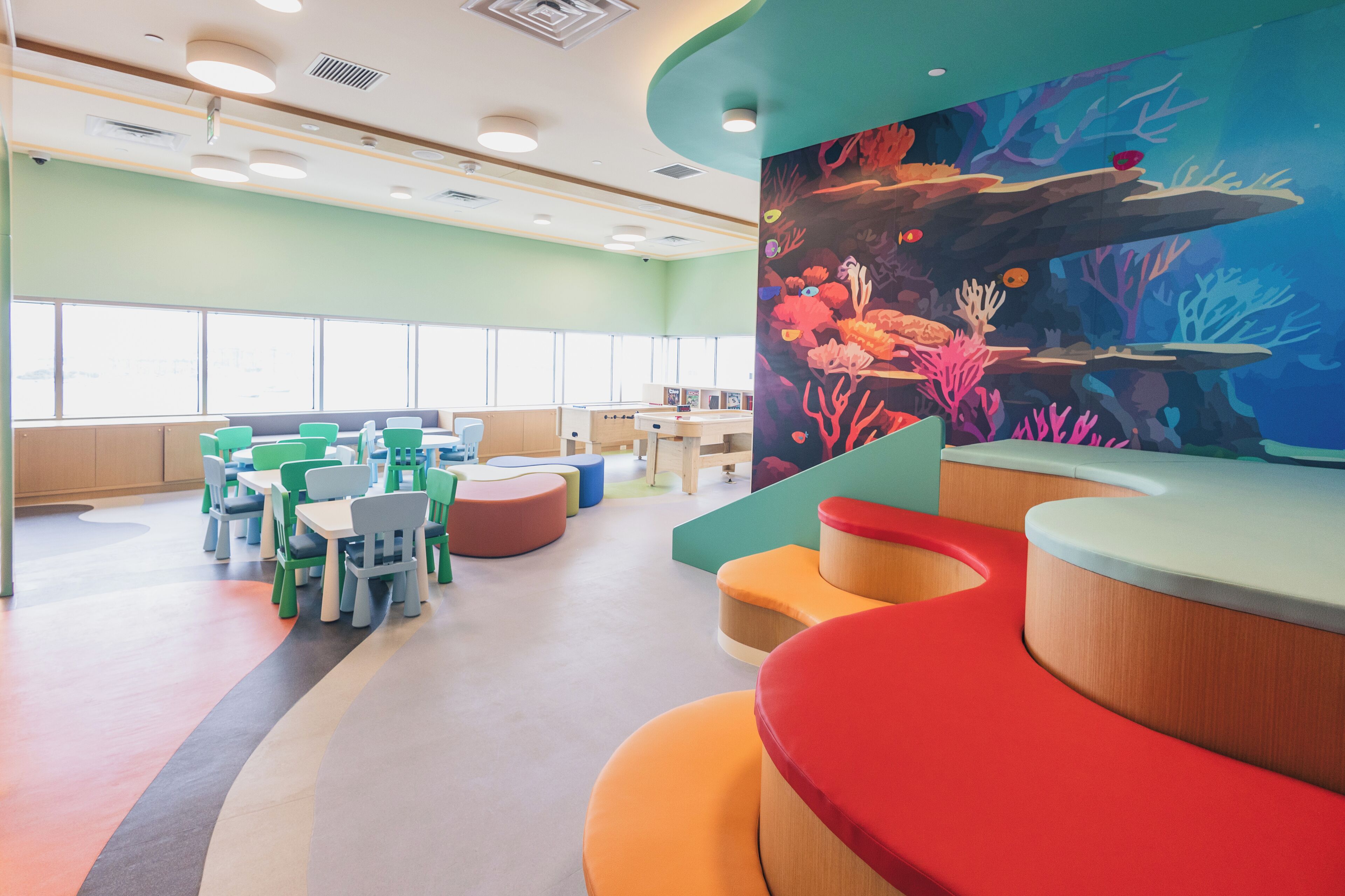 A children's play area with colorful seating and a large mural of an underwater scene.