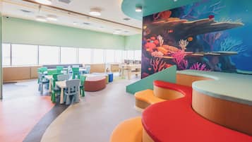 A children's play area with colorful seating and a large mural of an underwater scene.