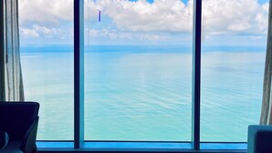 A room with a large window offering a view of the sea and sky.