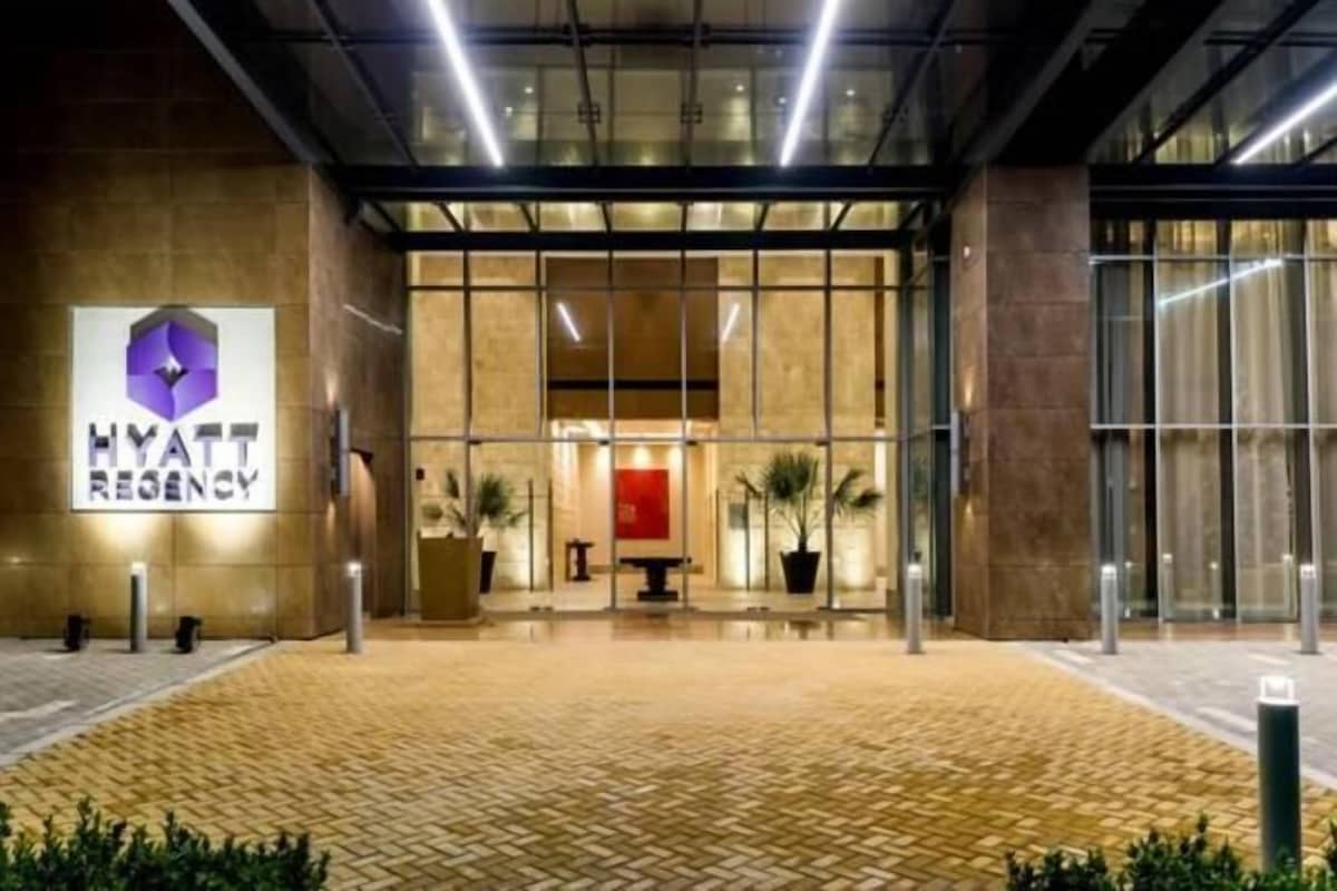 A Hyatt Regency hotel entrance with a modern design, large glass doors, and a tiled pavement.