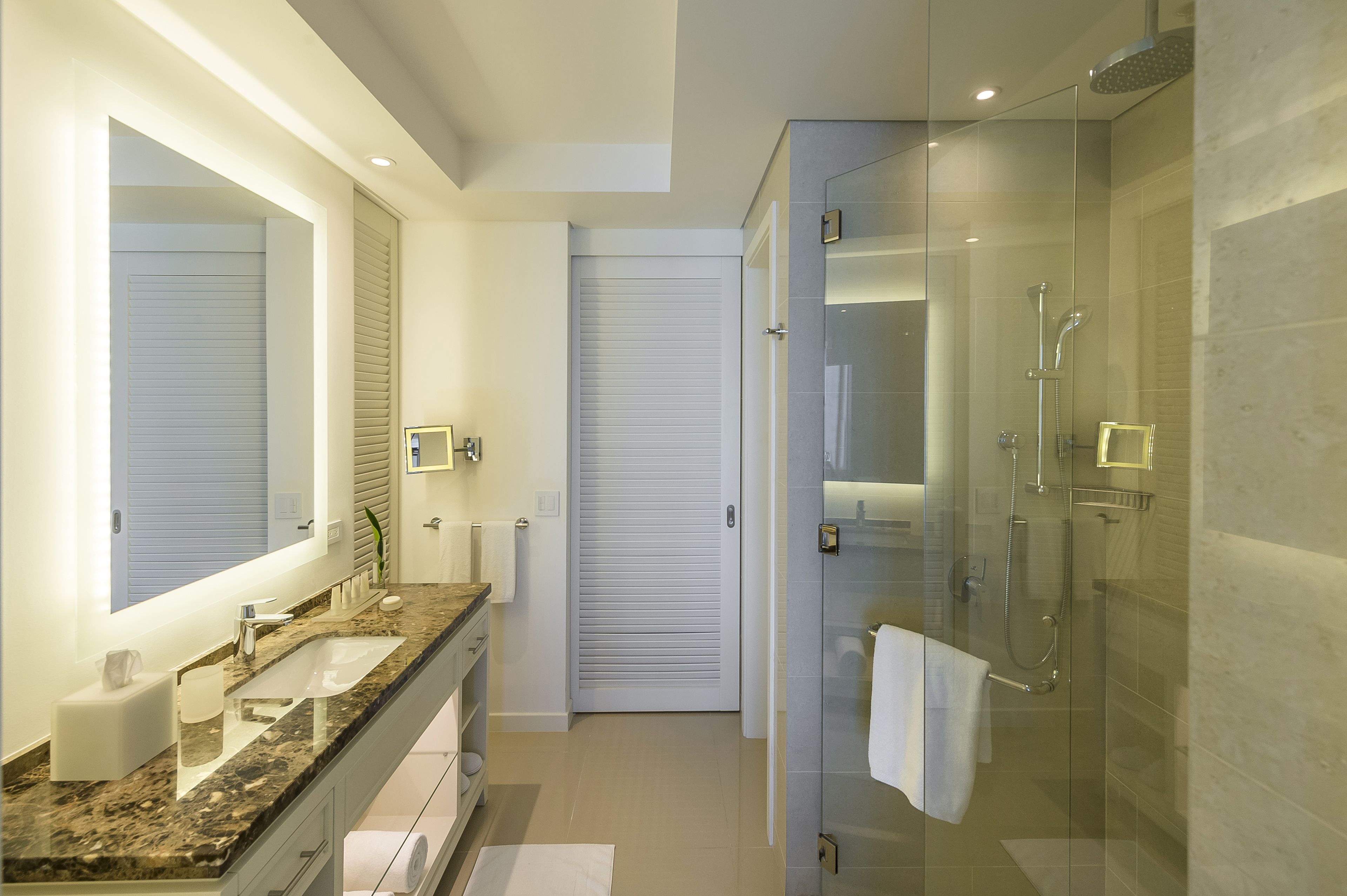 Un baño moderno con ducha acristalada, lavamanos doble y un espejo grande.