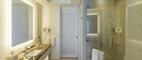 Un baño moderno con ducha acristalada, lavamanos doble y un espejo grande.