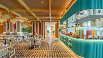 Un restaurante moderno con piso estampado, vigas de madera en el techo y una barra color turquesa con exhibición de bebidas.