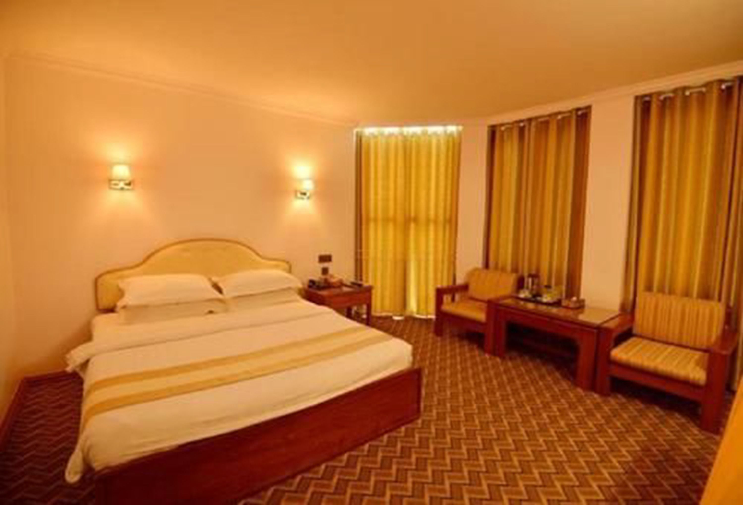 Habitación de hotel con una cama grande, dos mesitas de noche, una silla y un escritorio.