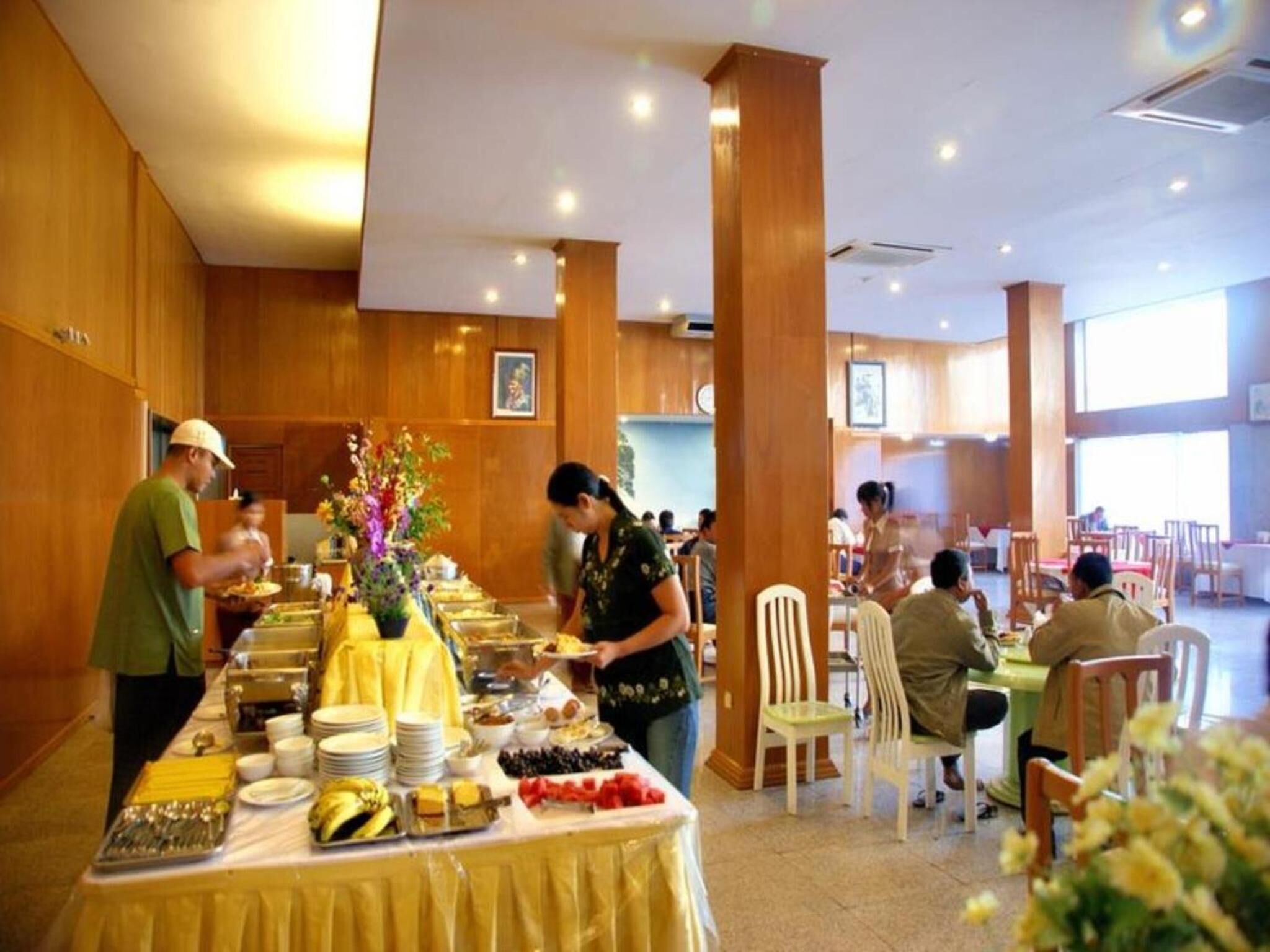 A buffet setup with various food items and a staff member serving.