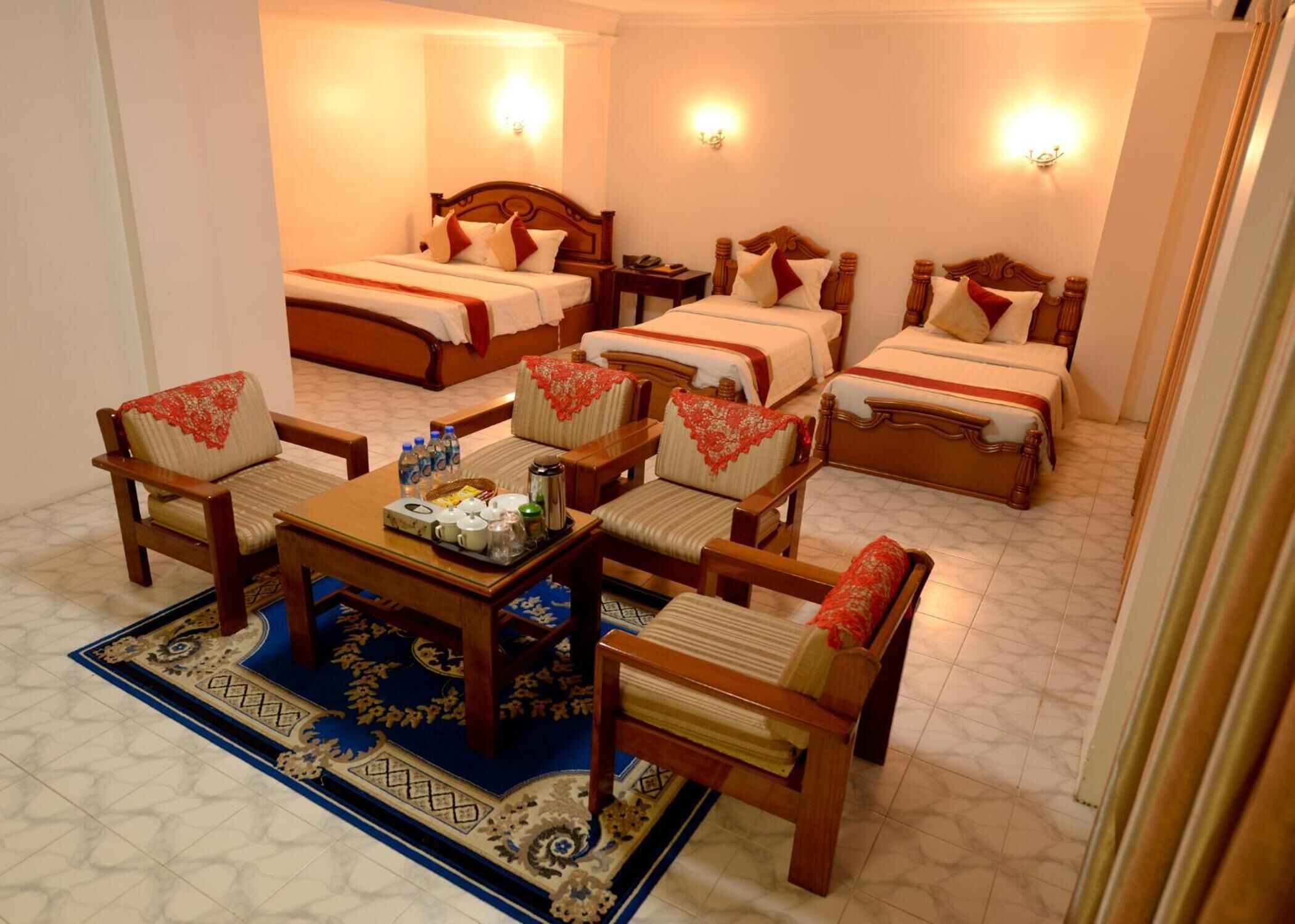 A hotel room with four beds, a dining table with chairs, and a coffee table.