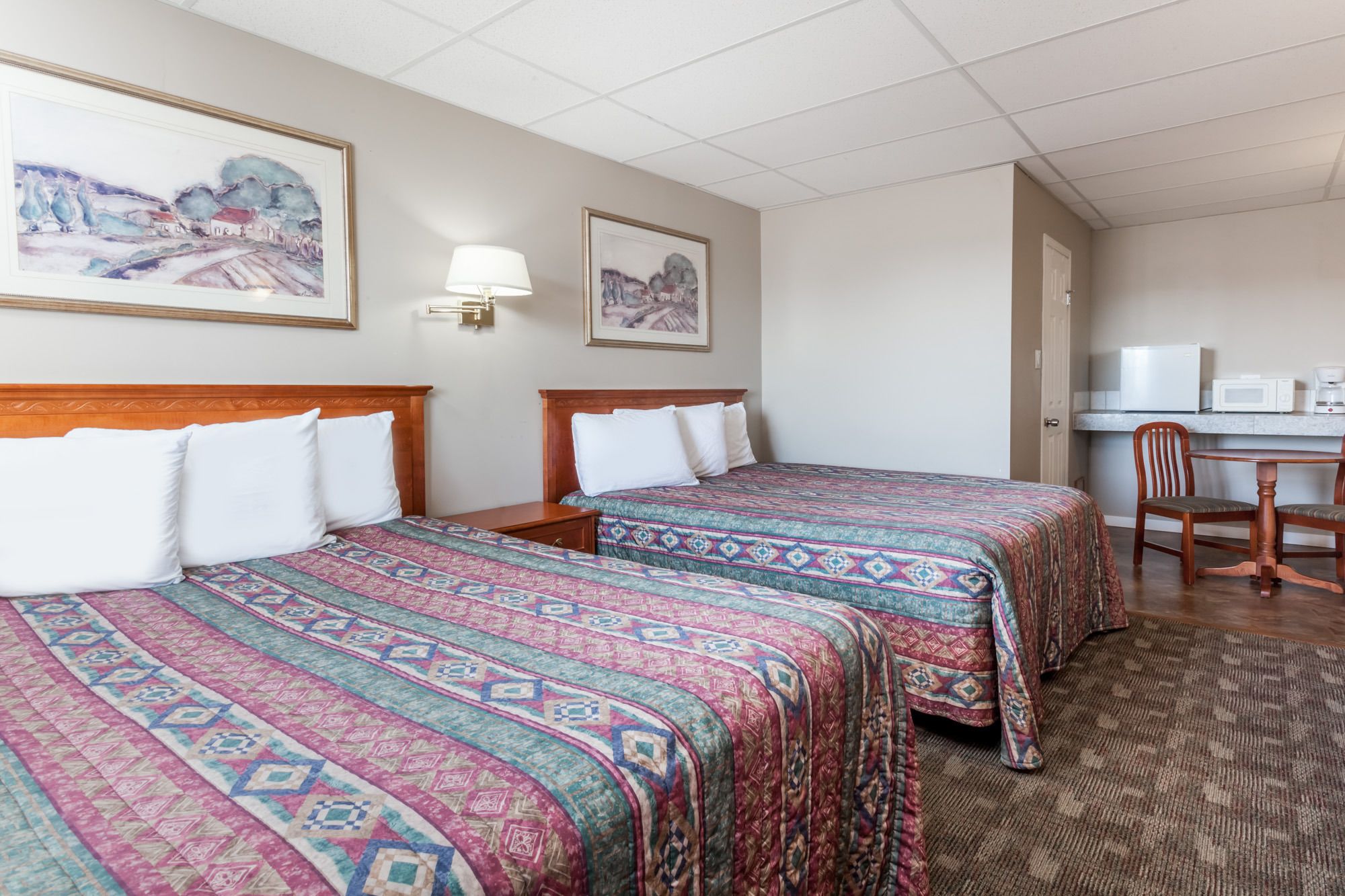 Une chambre d’hôtel avec deux lits, un bureau, une chaise et un four à micro-ondes.
