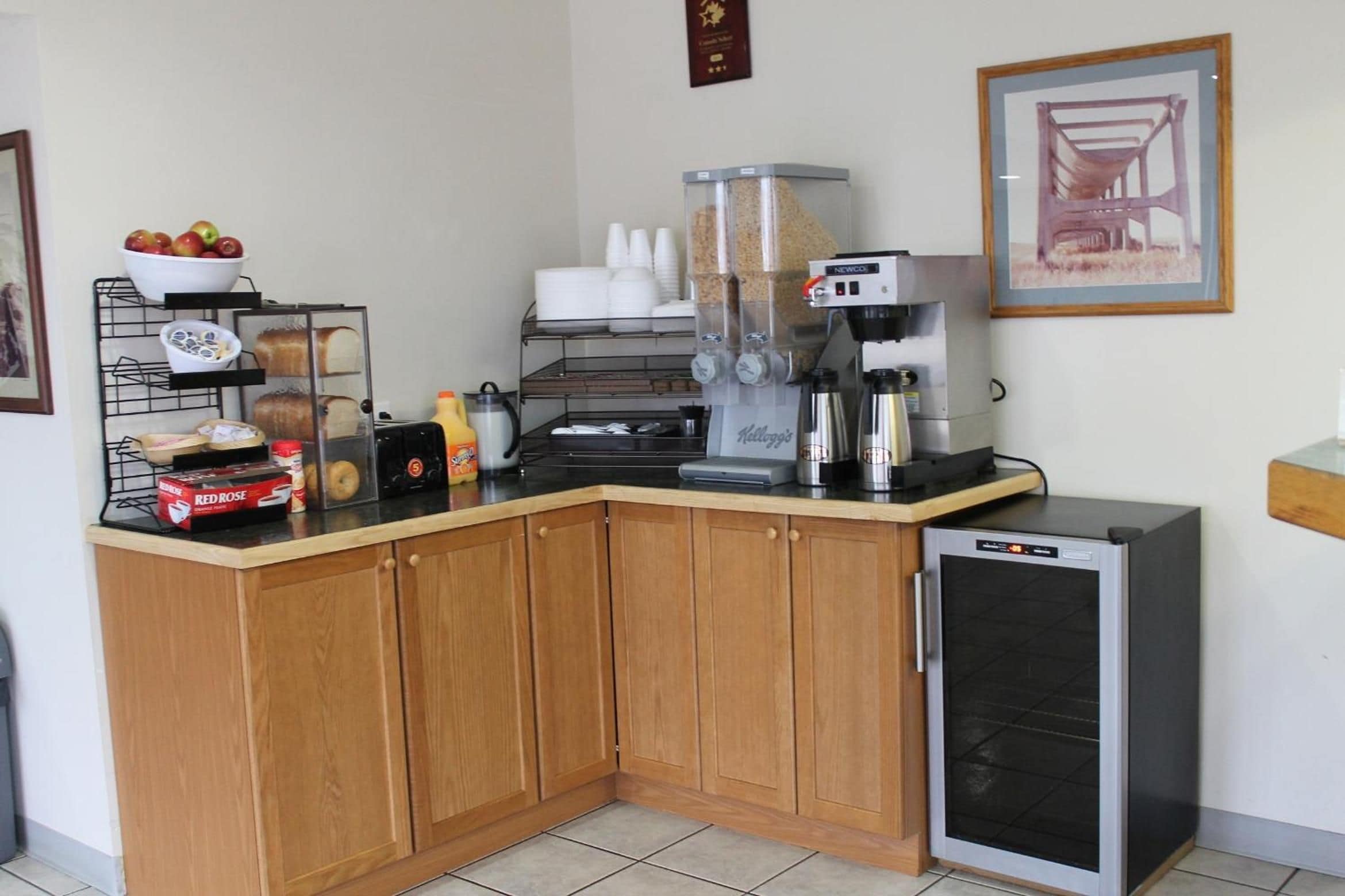 A small kitchenette with a coffee machine, a mini-fridge, and various food items on the counter.