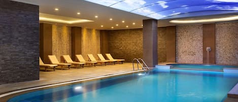 Een binnenzwembad en ligstoelen