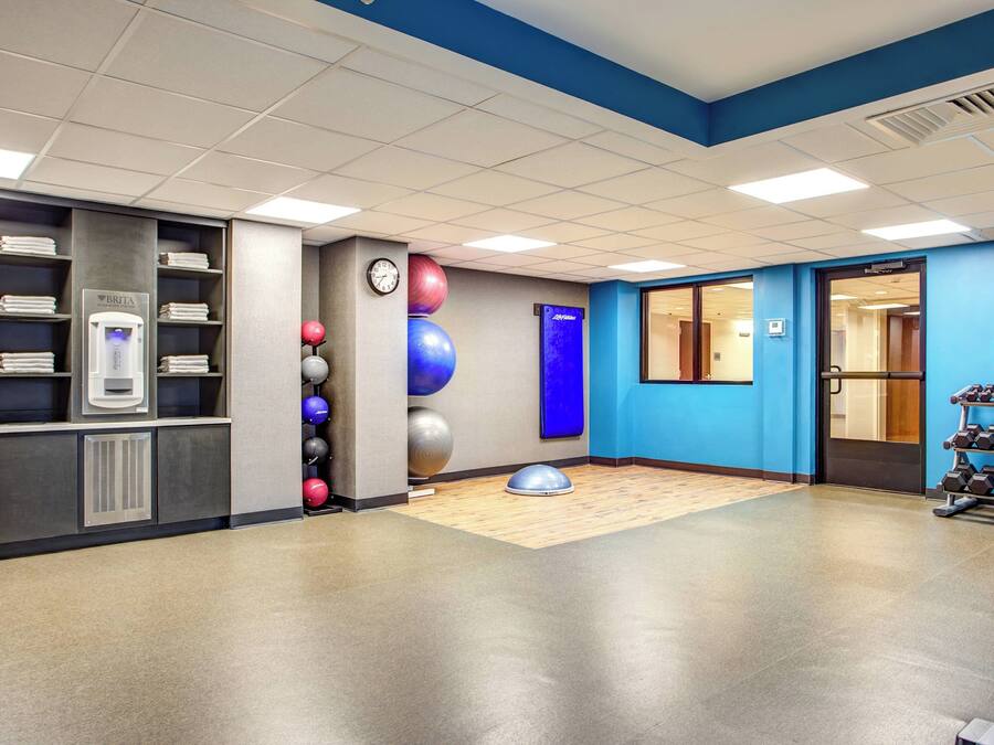 Ein Fitnessraum mit Trainingsgeräten, einer Uhr und einer Wand mit blauen Akzenten.