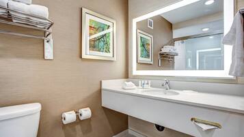 A modern bathroom with a white sink, a large mirror, and a towel rack.
