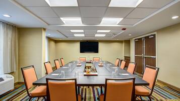 A conference room with a long table, chairs, and a flat-screen TV on the wall.
