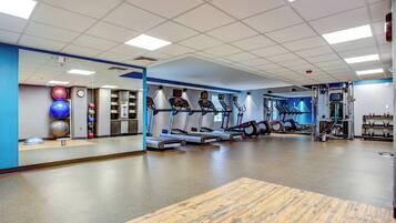 A gym with treadmills, elliptical machines, and exercise balls.