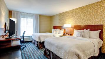 A hotel room with two beds, a desk with a computer, and a TV.